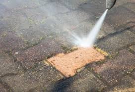 High-pressure water jet cleaning a wet brick on pavement