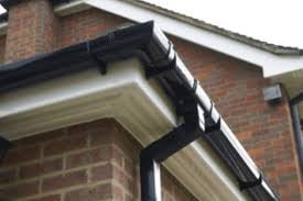 Black gutter and downspout on brick house exterior with white trim