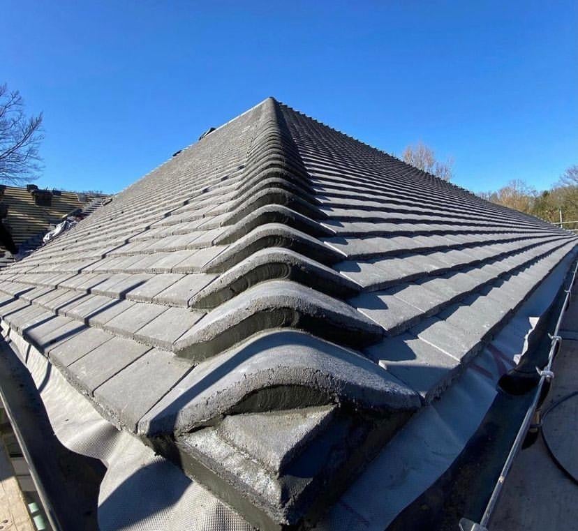 Roof with distinctive wavy asbestos tiles creating rippled pattern under clear blue sky